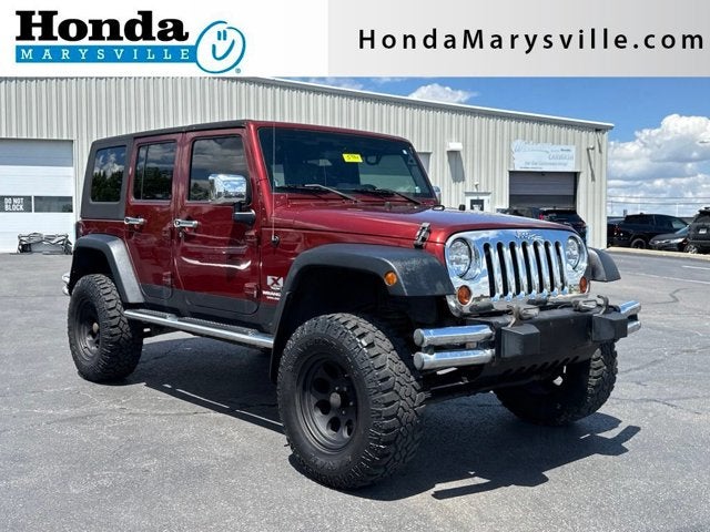 2009 Jeep Wrangler Unlimited X in Red Rock Crystal Pearlcoat/Black Soft Top — front three-quarter view